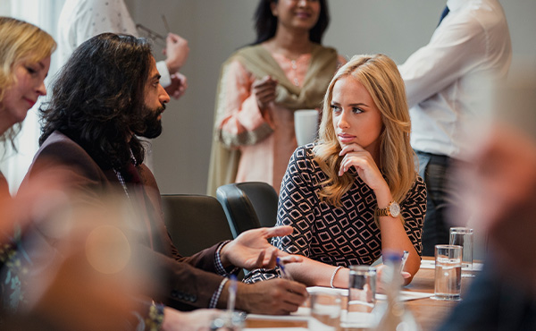 A meeting with two people talking sat at a table.
