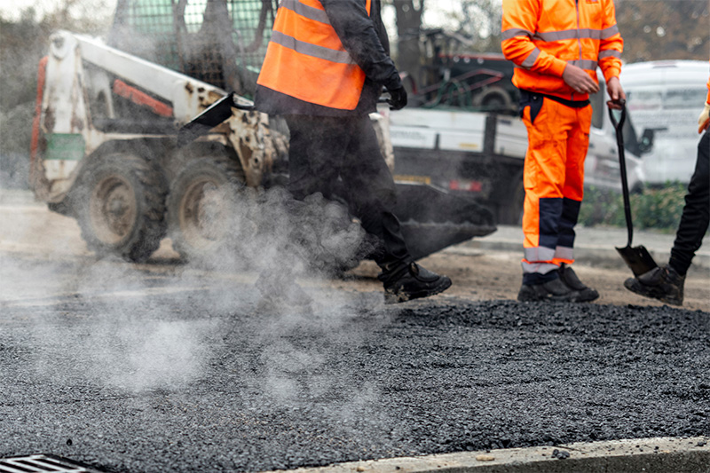 Photo of workers in high vis laying tarmac on a road.