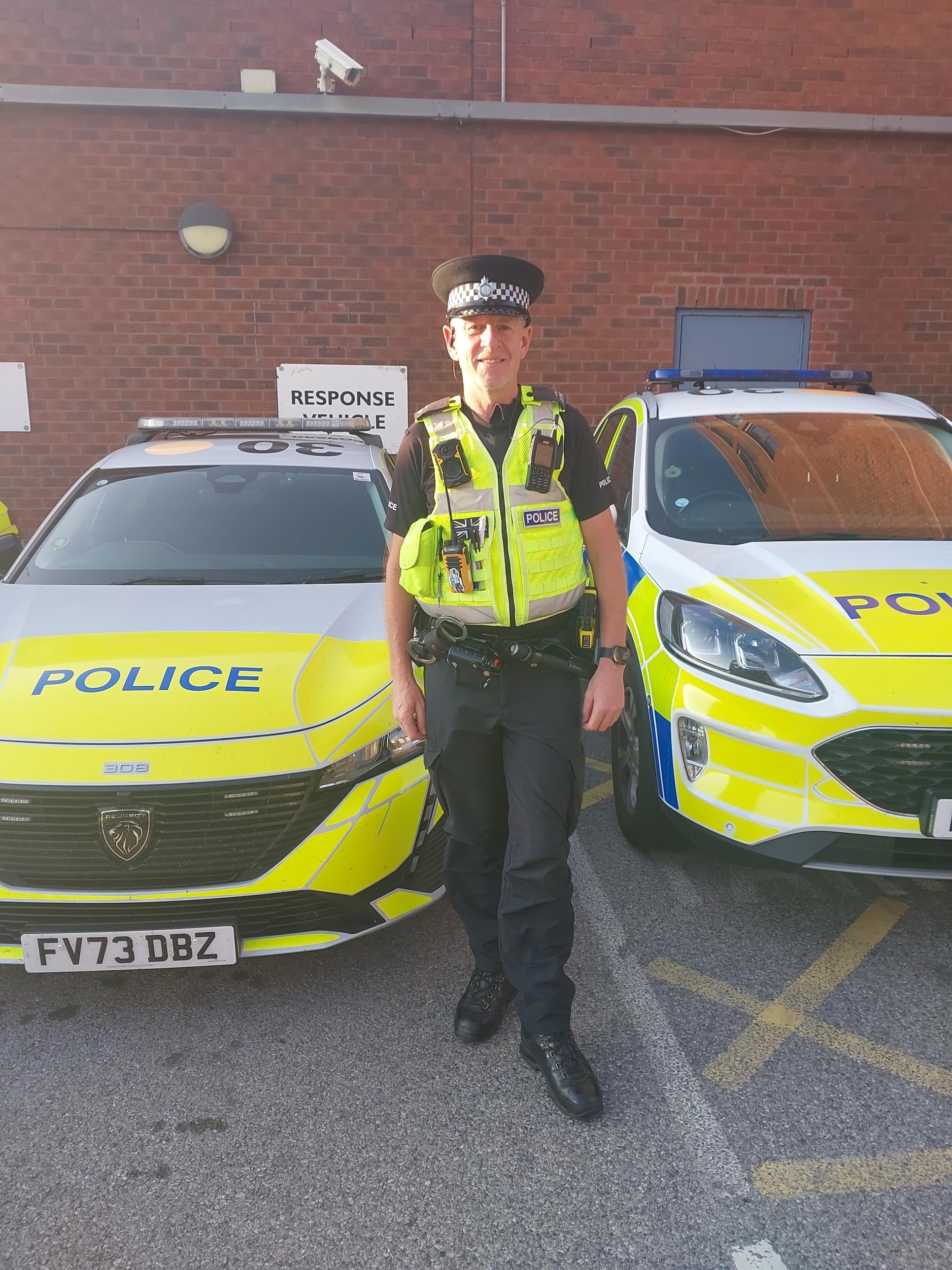A photo of PC Hind in front of a police car.