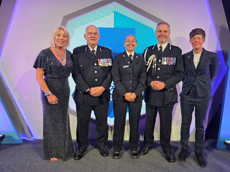 A group of officers in smart tunics smile at the camera at an awards evening.