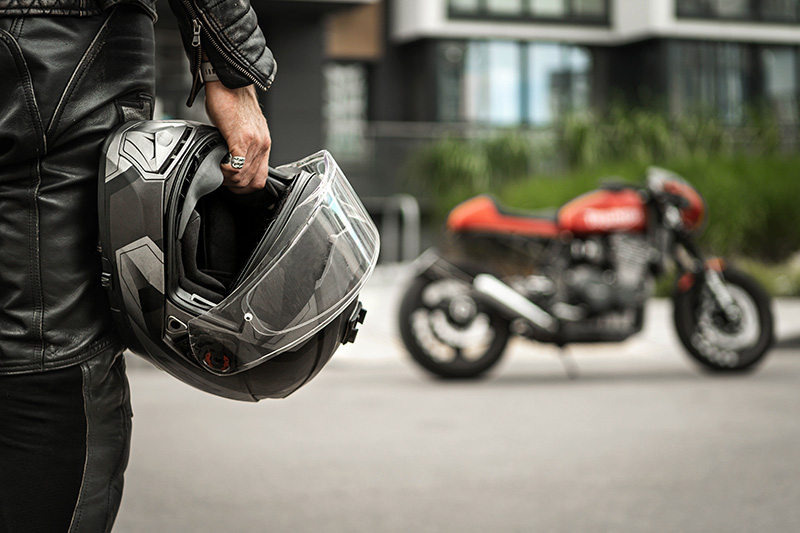 A person walking towards a motorbike wearing full leathers.