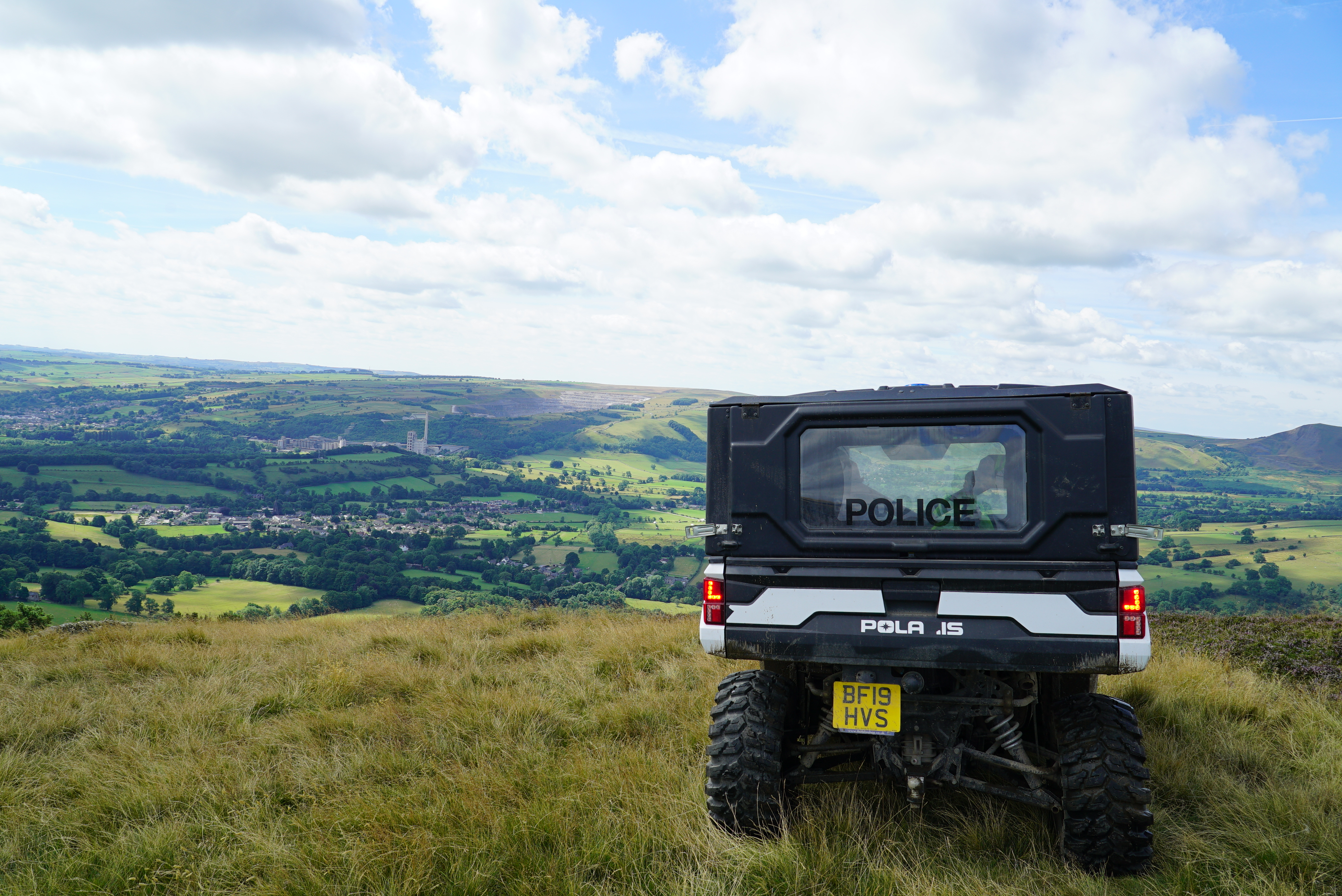 A black and white all terrain vehicle marked 'police' parked on a hill looking over Derbyshire countryside.