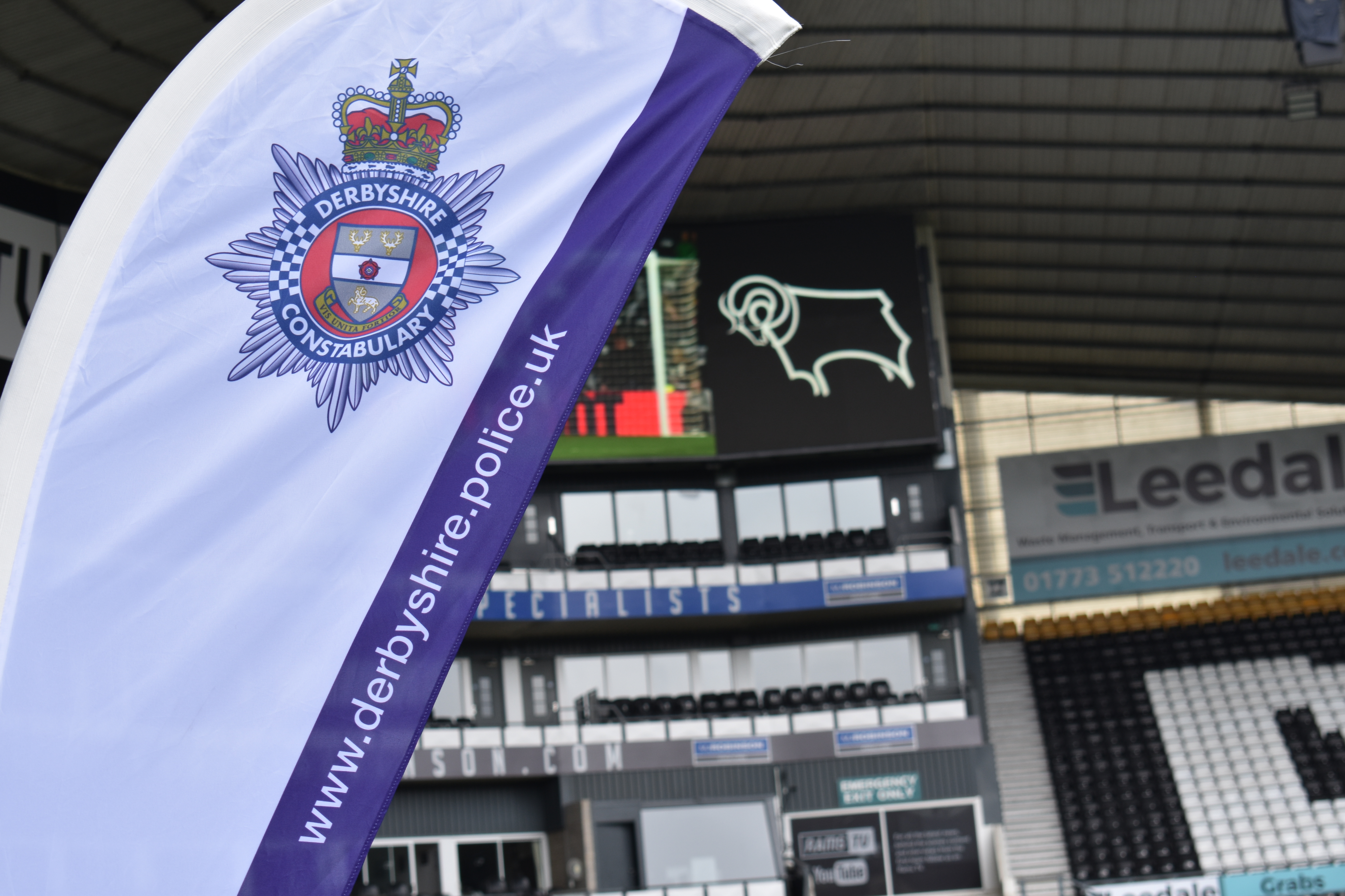 Derbyshire Constabulary crest on a flag within Derby County's Pride Park Stadium with black and white empty seats in the background.
