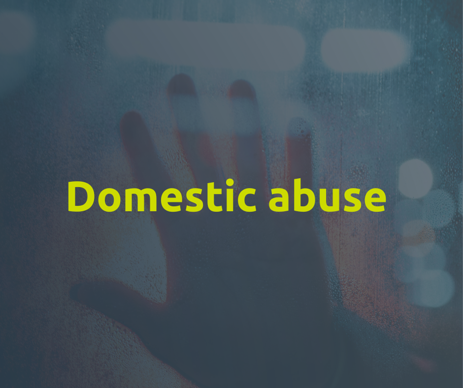 An image of a hand pressed up against some glass with the words domestic abuse
