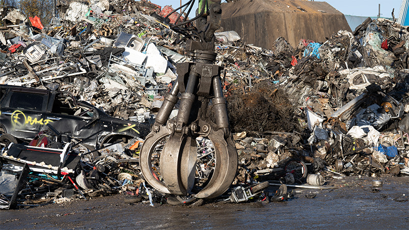 A pile of e-scooters being crushed with a giant claw.