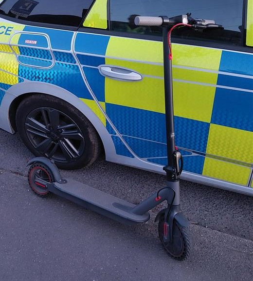 An e-scooter in front of a police car