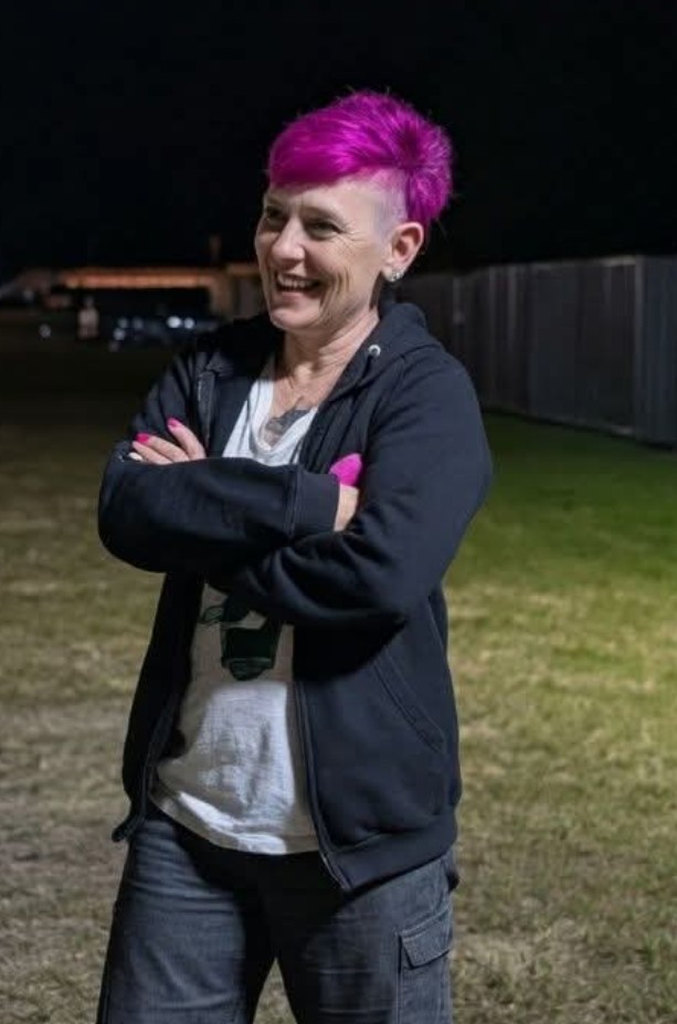 Woman with bright pink hair wearing a white t-shirt and black hoodie
